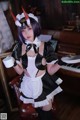 A woman dressed as a maid holding a cup of coffee.