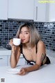 A woman sitting at a kitchen counter holding a cup of coffee.