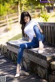 A woman sitting on a wooden bench in a park.