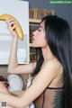 A woman holding a banana in front of her face.