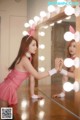 A woman in a pink dress standing in front of a mirror.