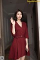 A woman in a red dress standing in a hallway.