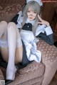 A woman in a maid outfit sitting on a couch.