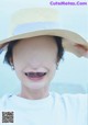 A woman wearing a straw hat smiles at the camera.