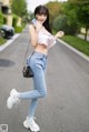 A woman in a pink top and blue jeans is walking down the street.