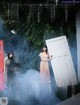 A woman standing in front of a red door with smoke coming out of it.