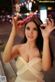 A woman in a white dress holding up a cell phone.
