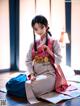 A woman in a kimono sitting on the floor.